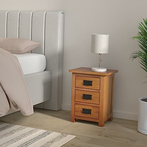 Bedroom with a wooden nightstand and lamp beside a bed.