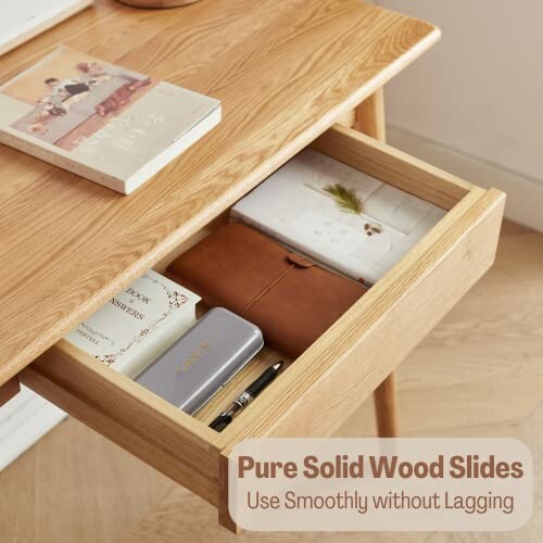 Open wooden desk drawer with books, a notebook, and a pencil.