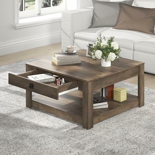 Wooden coffee table with drawer, books, and flowers in a living room.