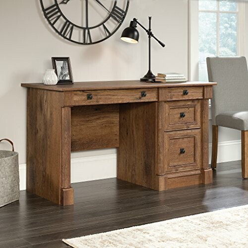 Wooden office desk with drawers and a chair in a home setting