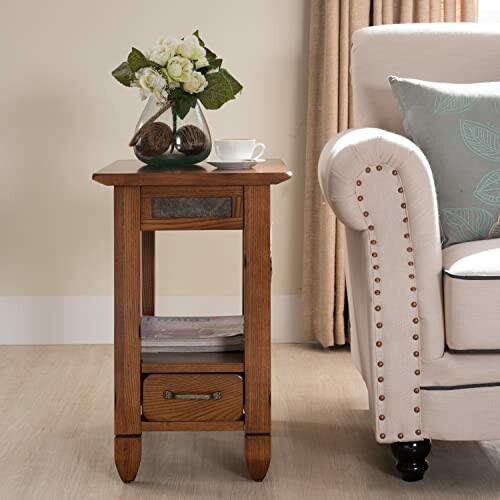 Wooden side table with flowers and teacup beside a sofa.